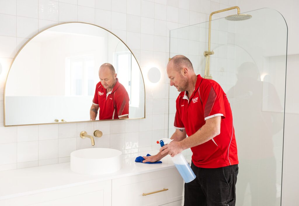 AustClean professional cleaner performing bathroom cleaning services in a modern residential bathroom