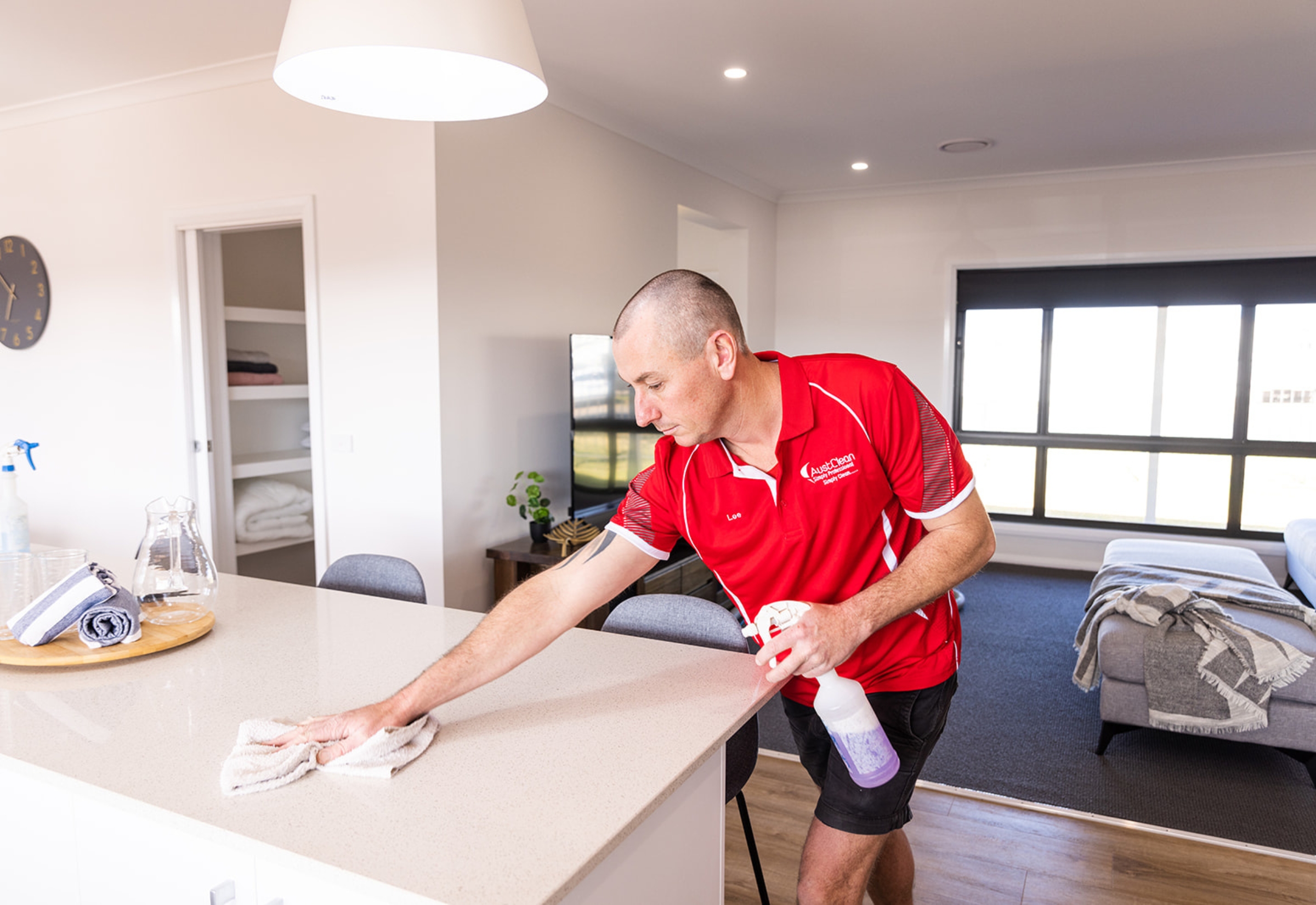 When Should You Book a Professional Spring Clean? 1 AustClean professional cleaner dusting table and furniture surfaces inside a residential home